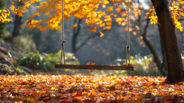 A swing hanging from a tree with a carpet of fallen leaves.